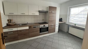 A modern kitchen with white and wood cabinets, a stainless steel sink, and a built-in oven.