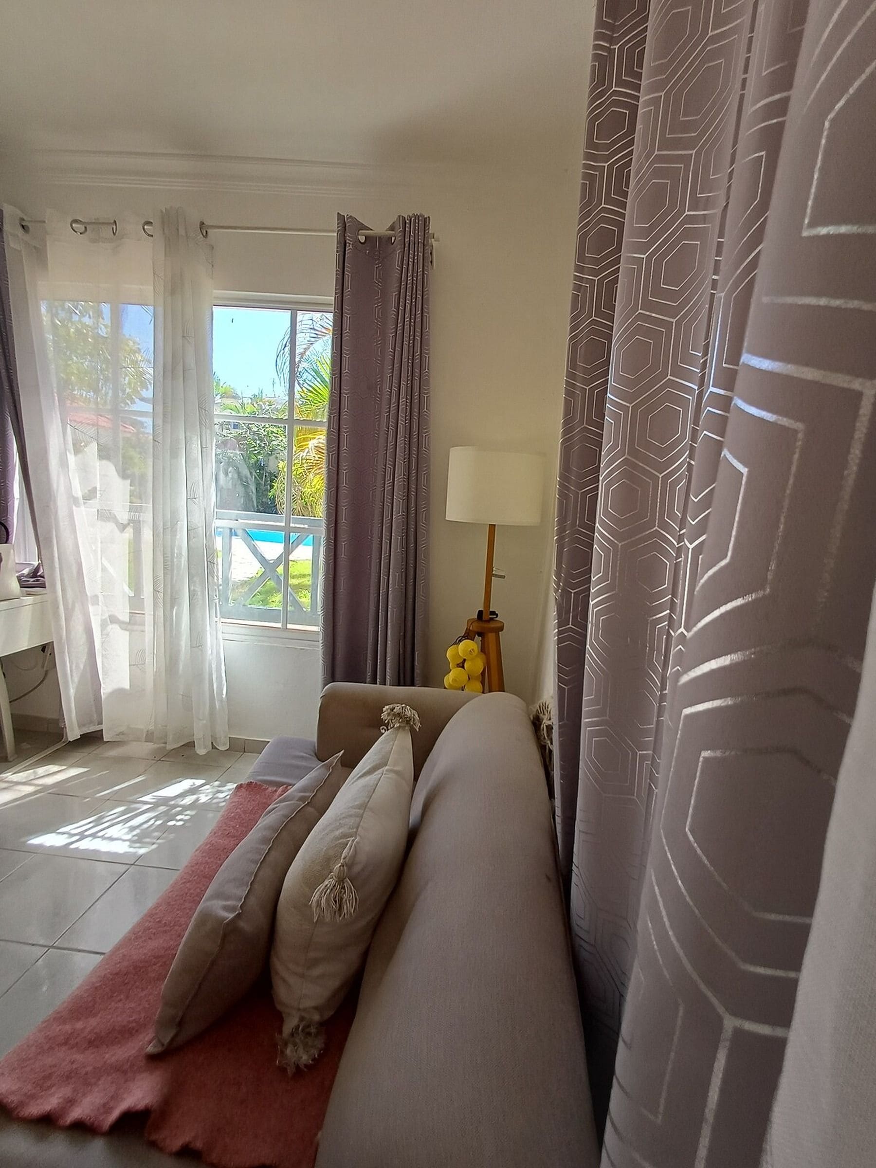 A bedroom with a bed, a lamp, and curtains.
