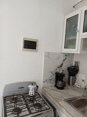 Eine Küche mit einem Gaskochfeld, einer Kaffeemaschine und einem Schrank mit Glastür.