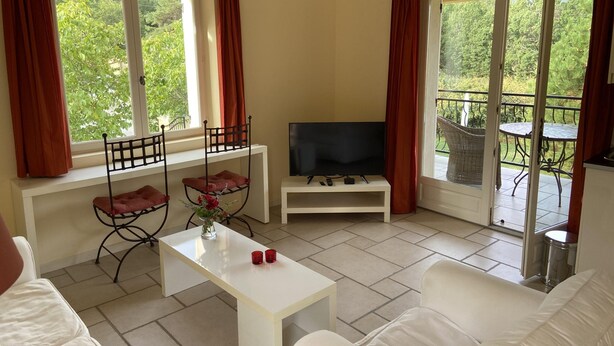 A living room with a TV, white sofa, and a table with red cups. - A sunny living room with a loggia and a beautiful view of Mont Ventoux (Montbrun-les-Bains)