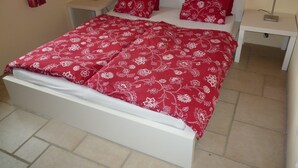 A bed with a red floral bedspread, two red pillows, and two bedside tables with lamps. - A sunny living room with a loggia and a beautiful view of Mont Ventoux (Montbrun-les-Bains)