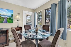 A dining area with a glass table, four chairs, a lamp, and a painting on the wall. - Myrtle Beach Resort 6306 (Myrtle Beach)