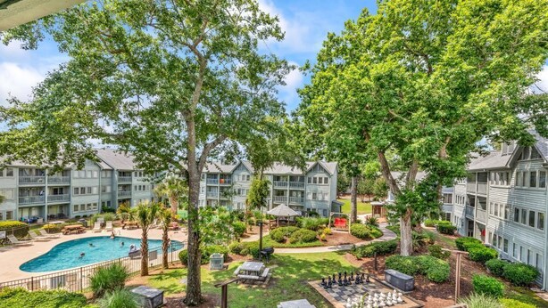 A pool area with lounge chairs, a chess table, and a gazebo.