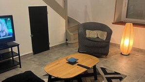 A living room with a TV, a sofa, a coffee table, and a lamp.