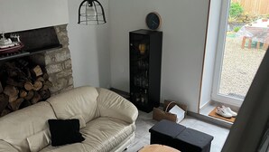 A living room with a beige sofa, a wooden coffee table, a black cabinet, and a stone fireplace.