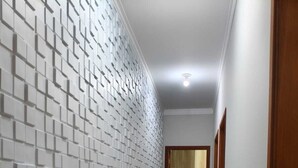 A hallway with a patterned wall and a wooden door at the end. - CASA FLORENÇA (Indaiatuba)