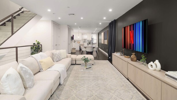 Un salon moderne avec un canapé, une table basse et un téléviseur fixé au mur.