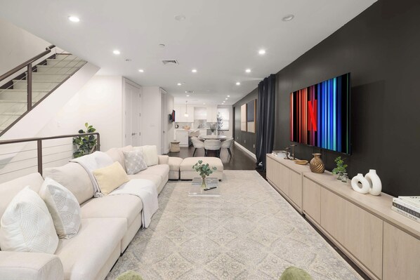 Una sala de estar moderna con sofá, mesa de centro y televisor montado en la pared.