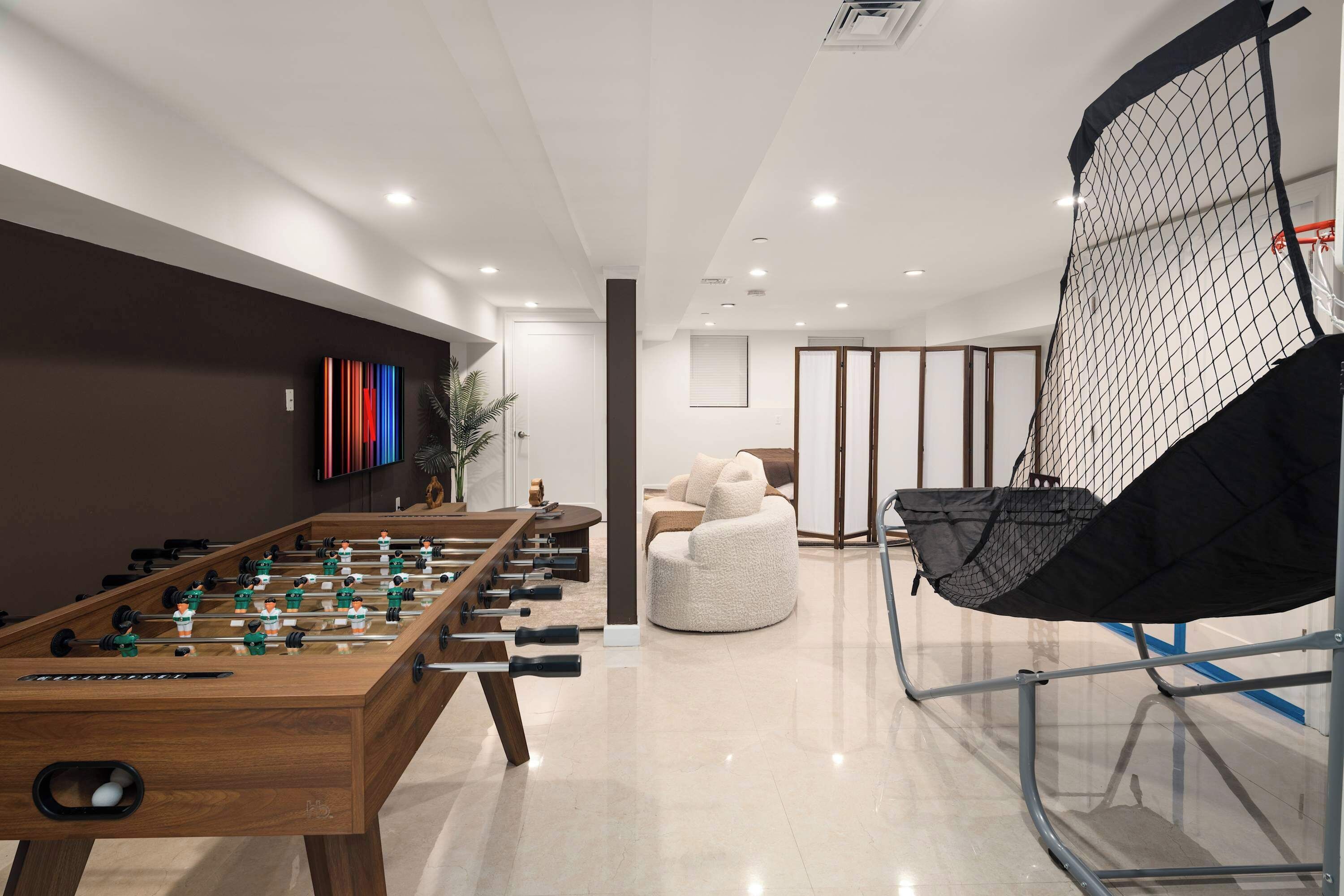 Una habitación moderna con una mesa de fútbol, un espacio de descanso cómodo y un ventanal grande.