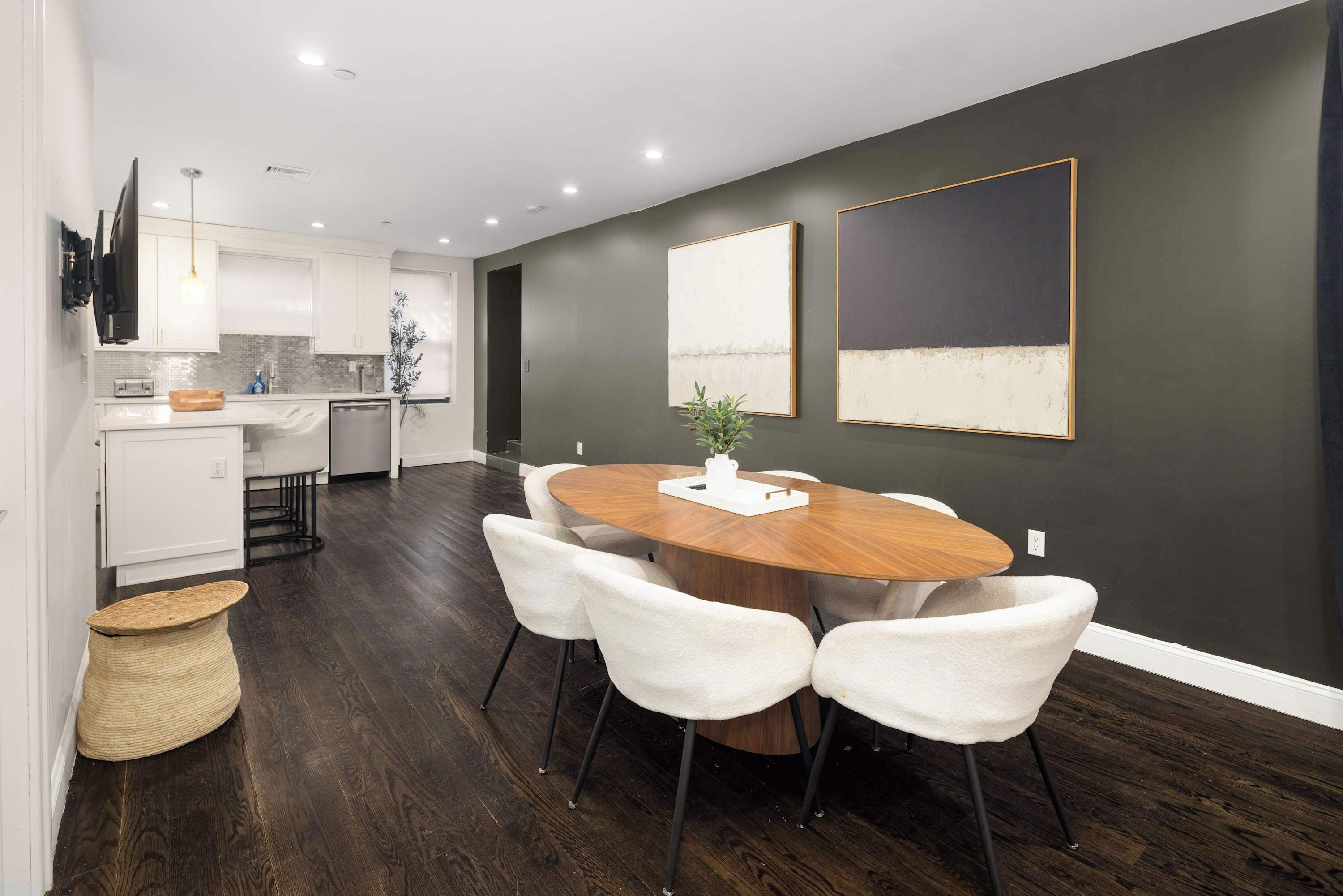 Una cocina moderna con armarios blancos, una mesa de comedor de madera y sillas blancas.
