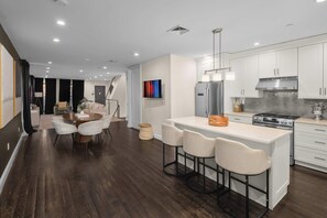 A modern kitchen with white cabinets, a stainless steel refrigerator, and a central island with bar stools.