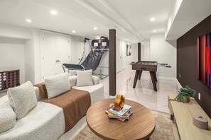 A modern living room with a sofa, coffee table, and a foosball table.