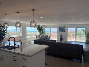 A modern kitchen with a large island, dining area with a view, and a living space with a sofa and a plant. - Spectacular lakeview, spacious, remodeled 3+2 bedroom, large lot for RVs, boats. (Perris)