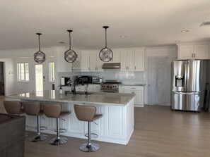 A modern kitchen with white cabinets, stainless steel appliances, and a central island with bar stools.
