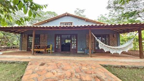 A two-story building with a covered porch, a hammock, and a bench. - CASA ROSIER – Charme rústico em Lençóis (Lençóis)