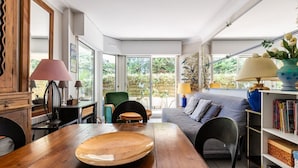 A modern living room with a wooden dining table, a sofa, and a bookshelf. - Emerald apartment with beach access in Pereire (Arcachon)