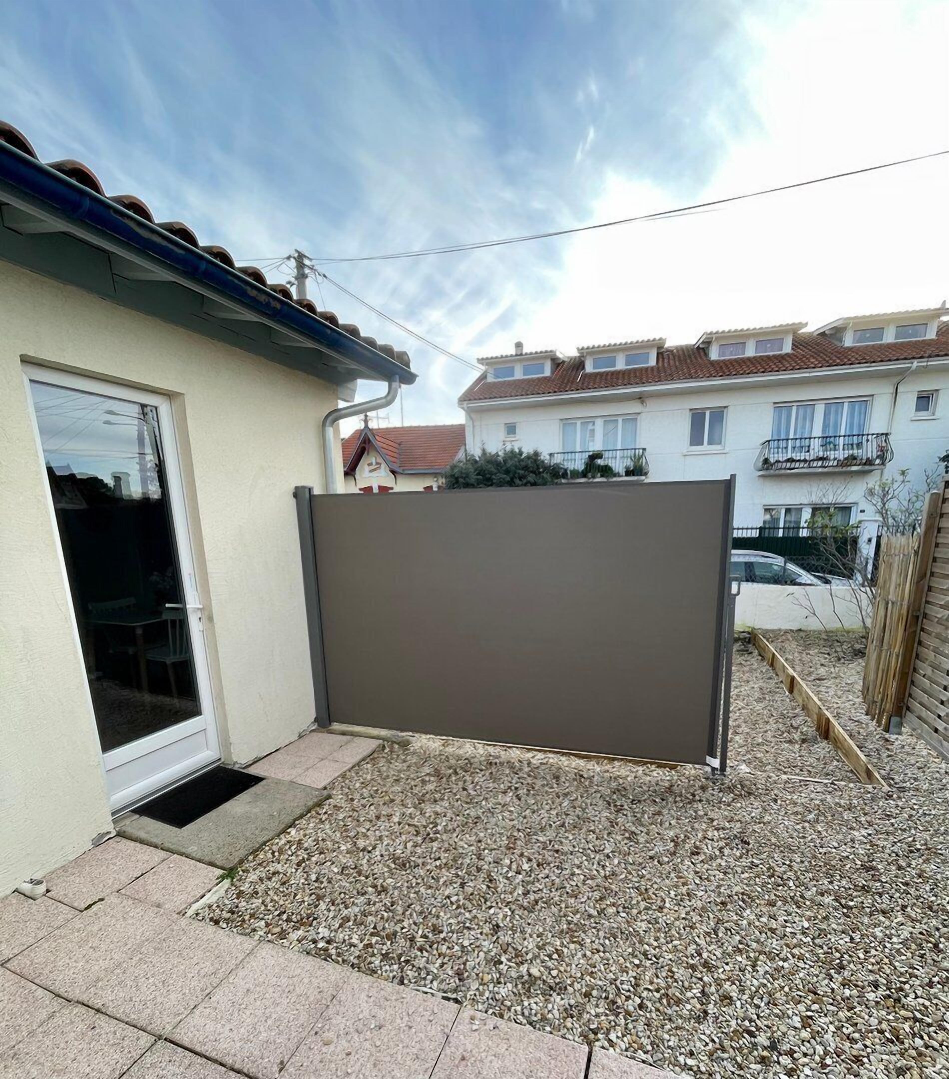 Un quartiere residenziale con una casa caratterizzata da una porta scorrevole in vetro, un vialetto sterrato e un recinto in legno.