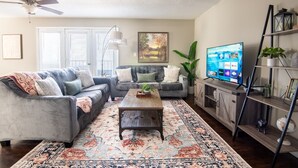 A living room with a gray sofa, a wooden coffee table, and a TV on a wooden stand. - Ridge Retreats Unit B - Balcony/Wifi/4 Queen Beds (Birmingham)