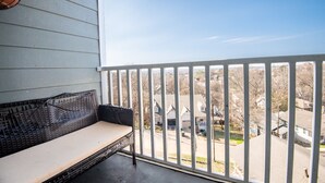 A balcony with a wicker sofa and a view of a residential area. - Ridge Retreats Unit E- WiFi/4 Queen Beds/Groups (Birmingham)