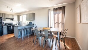 A modern kitchen with grey cabinets, a central island with bar stools, and a dining table with chairs. - Ridge Retreats - Unit F: King Bed/Free Parking/TVs (Birmingham)