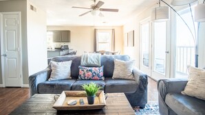 A living room with a gray sofa, a wooden coffee table with a tray, and a ceiling fan. - Ridge Retreats - Unit F: King Bed/Free Parking/TVs (Birmingham)