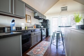 A modern kitchen with dark cabinets, a built-in oven, and a coffee maker.