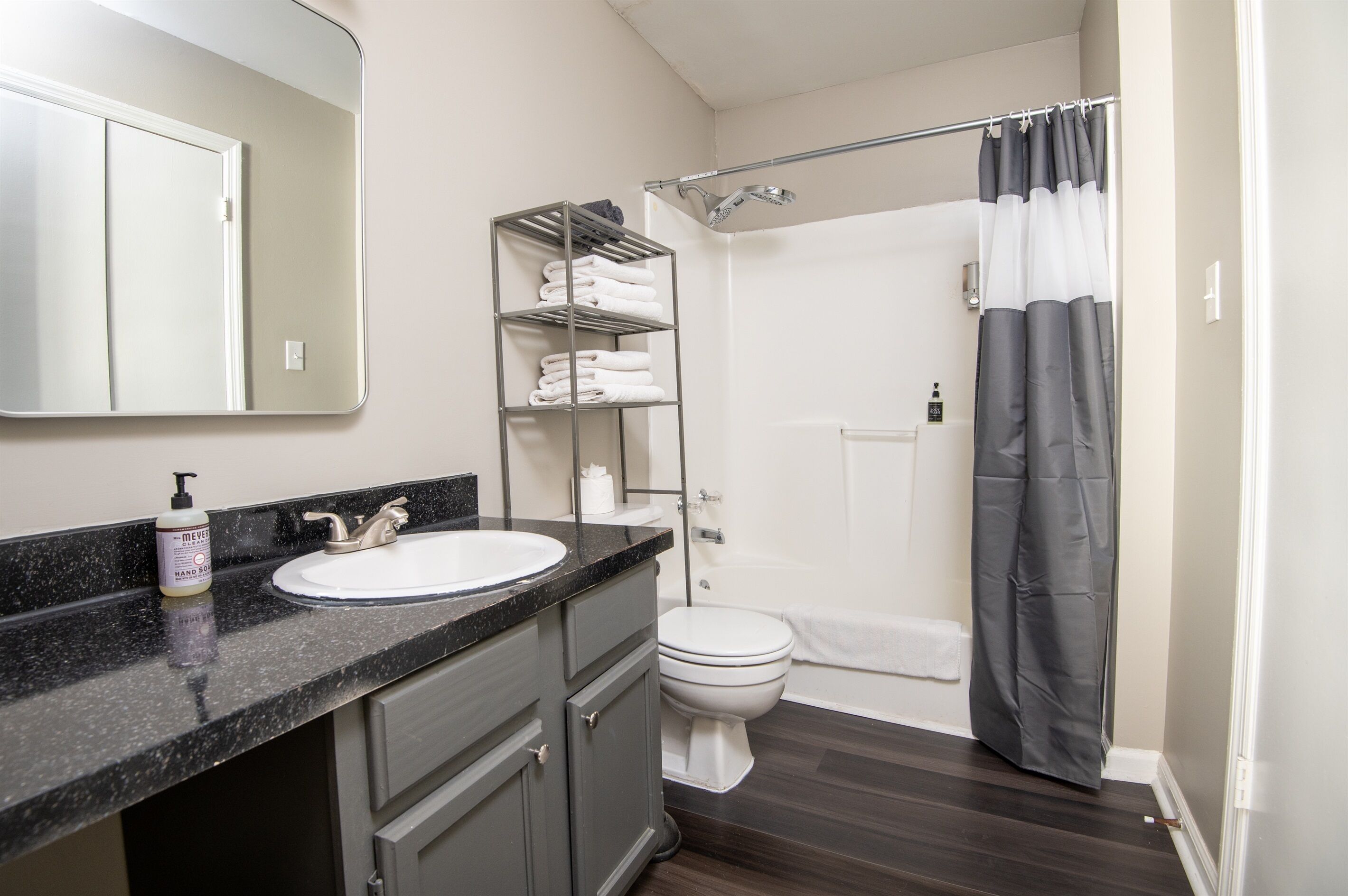 A bathroom with a white sink, a mirror, a towel rack, a shower curtain, and a toilet.