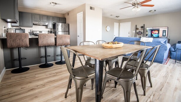 Una cocina moderna con armarios grises, una mesa de comedor de madera y sillas de metal.
