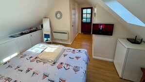 Een slaapkamer met een bed, een dressoir, een spiegel, een radiator, een televisie en een raam.
