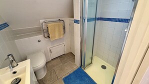 Een badkamer met een wit wastafelmeubel, toilet en douchecabine.