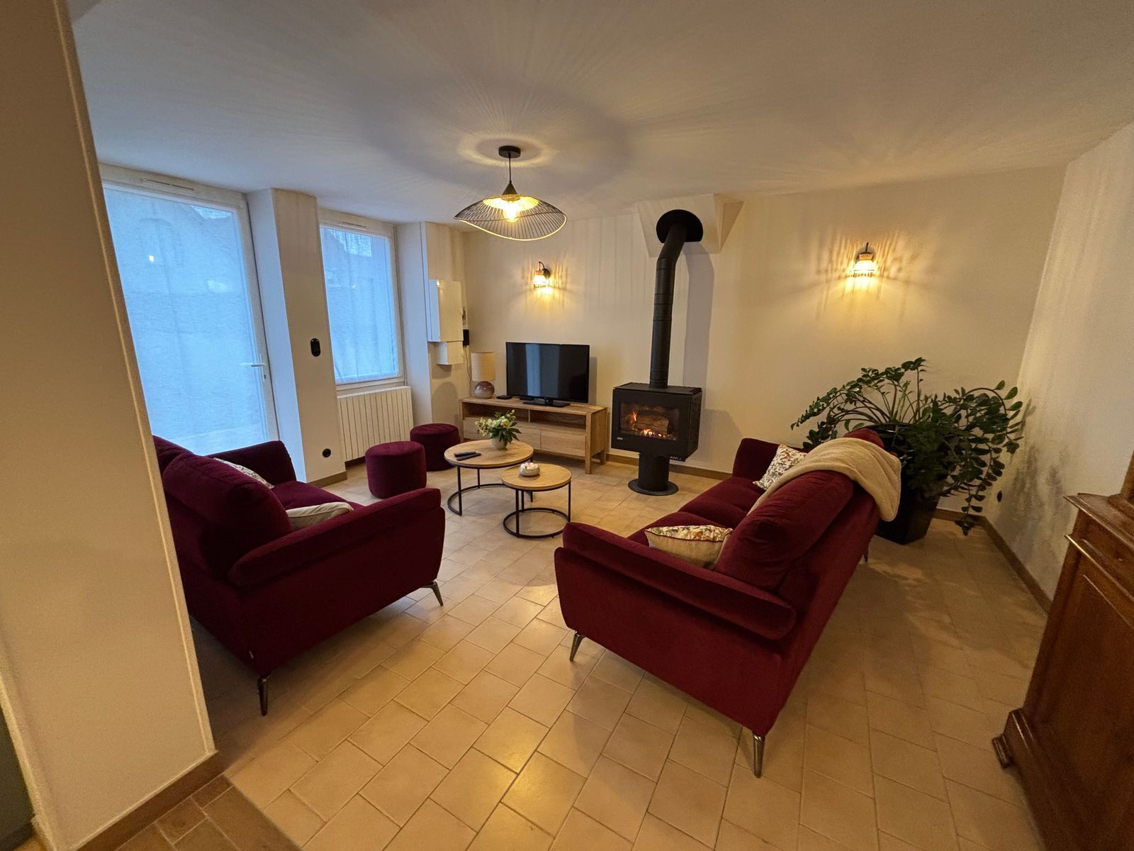 A living room with a fireplace, red sofas, a TV, and a plant.