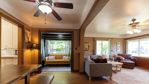 A spacious living room with a wooden floor, a sofa, a loveseat, a dining table, and a ceiling fan. - Spacious, Central Location 4-bedroom, King Beds - Walk to Dining, Brewery, Park (Spokane)