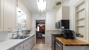 A compact kitchen with white cabinetry, a wooden countertop, a built-in microwave, and a coffee maker. - Spacious, Central Location 4-bedroom, King Beds - Walk to Dining, Brewery, Park (Spokane)