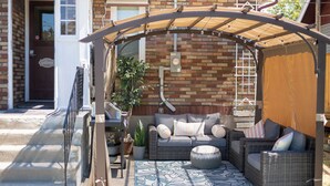A covered patio with wicker furniture, a potted plant, and a welcome sign. - Spacious, Central Location 4-bedroom, King Beds - Walk to Dining, Brewery, Park (Spokane)