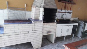 Una cocina exterior de ladrillo con chimenea, un lavamanos y una encimera.
