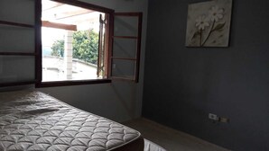 Un dormitorio con una cama, una ventana y un cuadro de flores colgado en la pared.