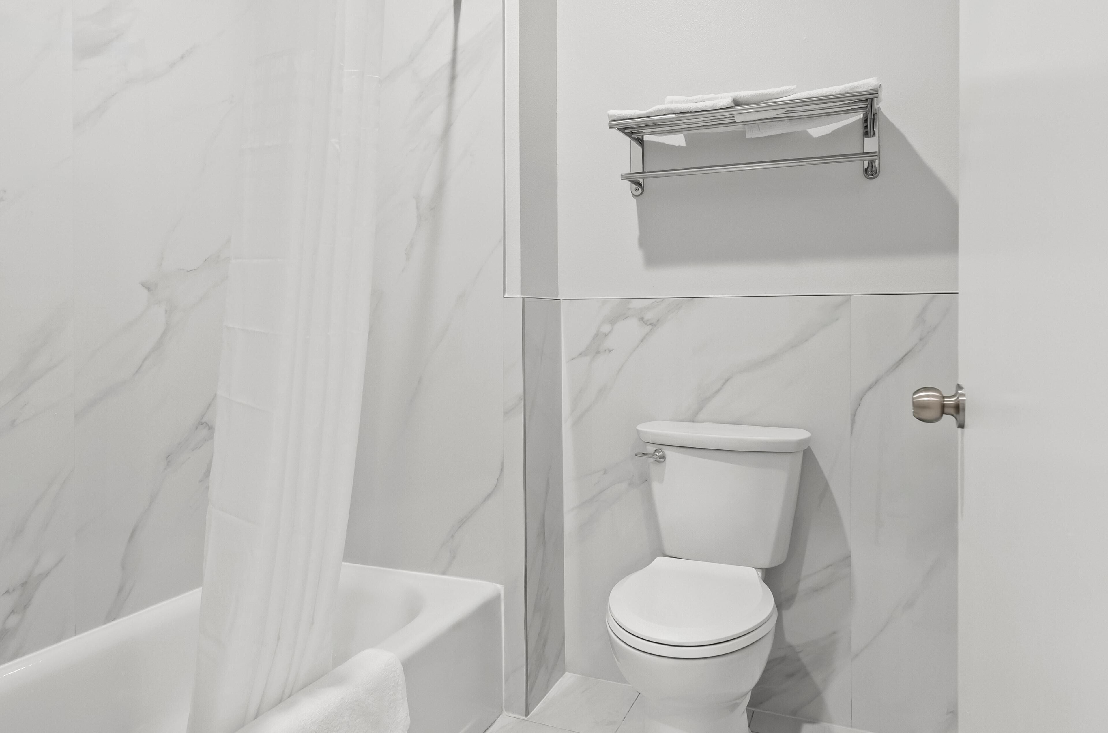 A bathroom with a toilet, a shower curtain, and a towel rack.