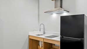 A kitchen with a black refrigerator, a stainless steel sink, and a wooden countertop. - Americas Best Value Inn & Suites Tomball Grand Parkway (Tomball)