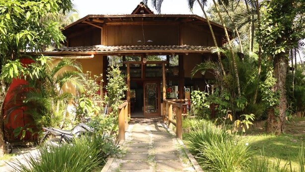 A wooden building with a stone pathway leading to a wooden entrance. - Chalé do Mar I (São Francisco do Sul)