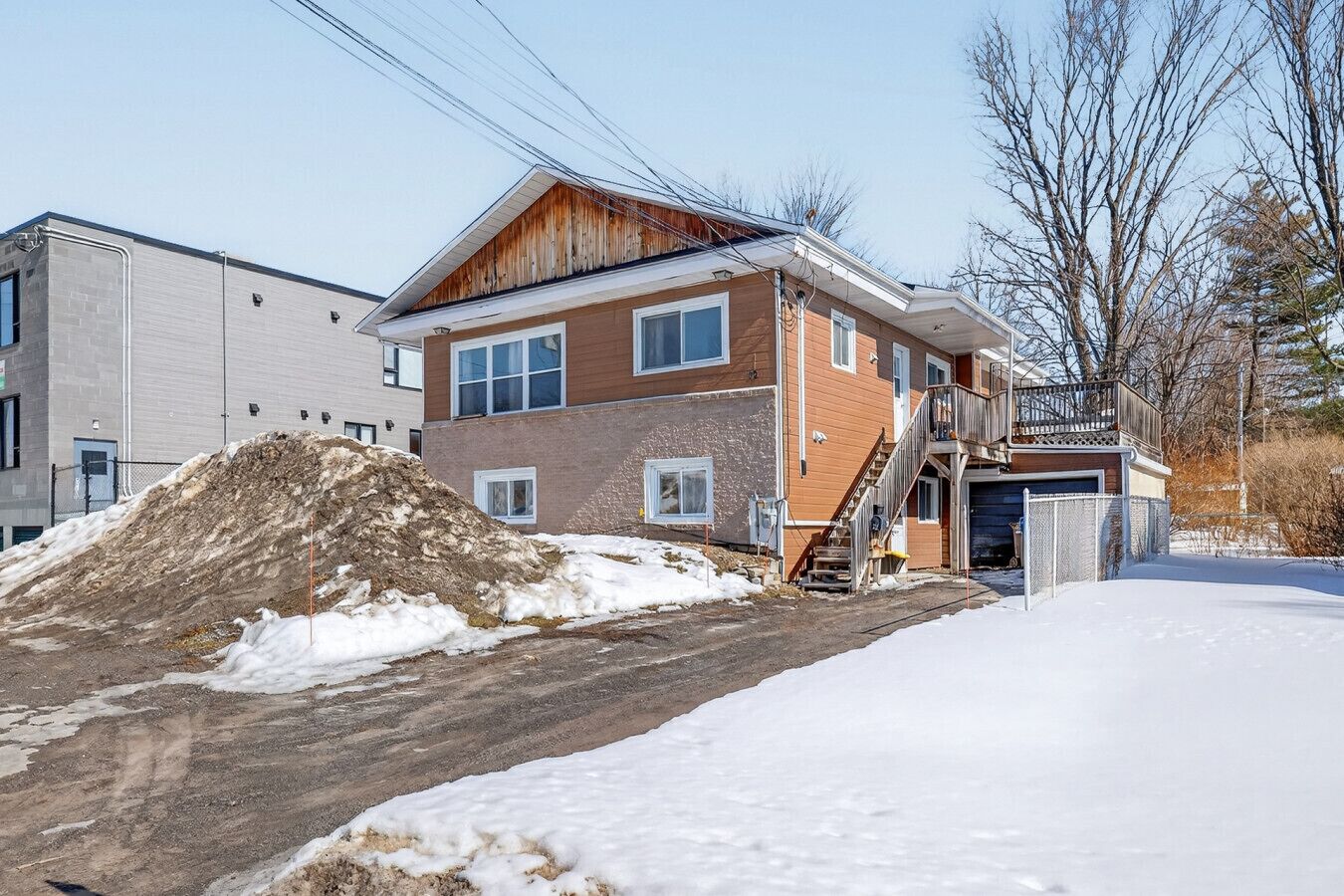 Un bâtiment à deux étages, avec une façade en bois et un garage.