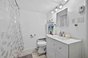 A modern bathroom with a toilet, sink, and shower curtain. - Charming Apartment by Aylmer Marina (Gatineau)