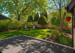 A backyard with a paved area, a wooden fence, and a small table with chairs.