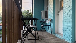 Eine Holzterrasse mit Tisch und Stühlen, einer Klimaanlage und einer blau gestrichenen Wand.
