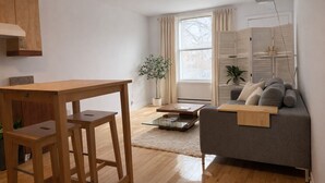 Ein modernes Wohnzimmer mit einem Holzesstisch, einem grauen Sofa und einem Glastisch.