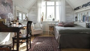A cozy bedroom with a bed, a desk, a chair, and a window with curtains.