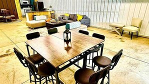 A spacious room with a large wooden table surrounded by chairs, a sofa, and a television in the background. - Huron Hideaway - Great Indoor & Outdoor Spaces! (Huron)
