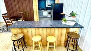 A kitchen with a wooden island, bar stools, and a refrigerator. - Huron Hideaway - Great Indoor & Outdoor Spaces! (Huron)