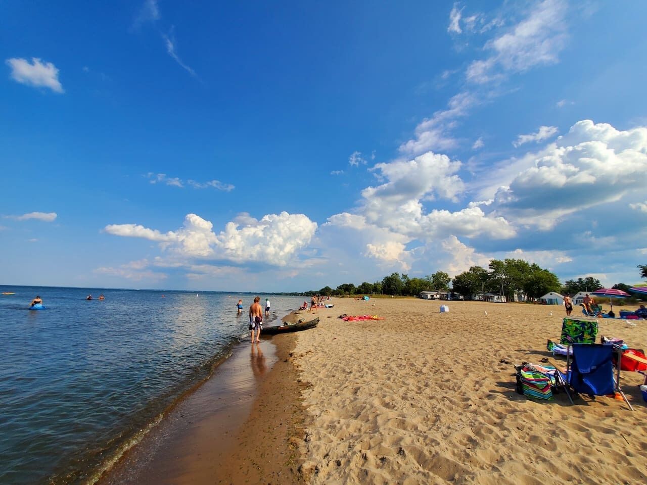 A beach with clear skies, calm water, and people near the shore.