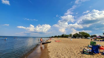 A beach with clear skies, calm water, and people near the shore.