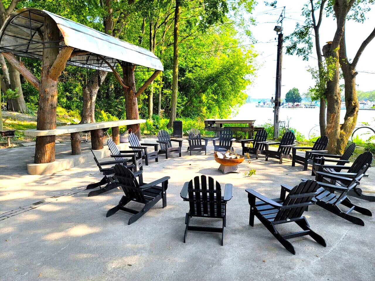 An outdoor seating area with Adirondack chairs, a fire pit, and a covered pavilion.
